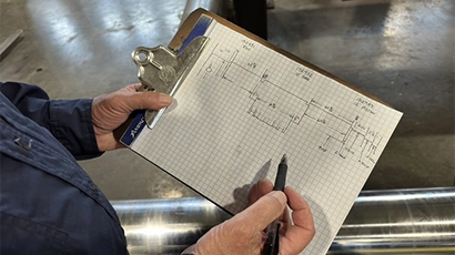 Close-up of male technician's hands drawing hydraulic facility floor plan on graph paper