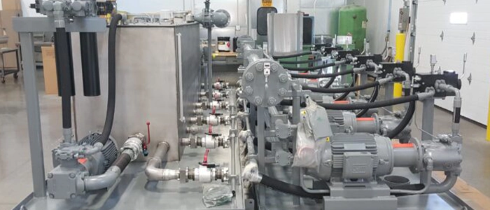 Image of a large custom hydraulic power unit with six gray motors in repair and services facility
